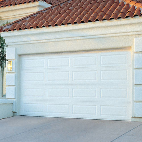 A white steel garage door on a home. Garage doors come in all different types of materials, but steel is a popular choice due to its durability and affordability.